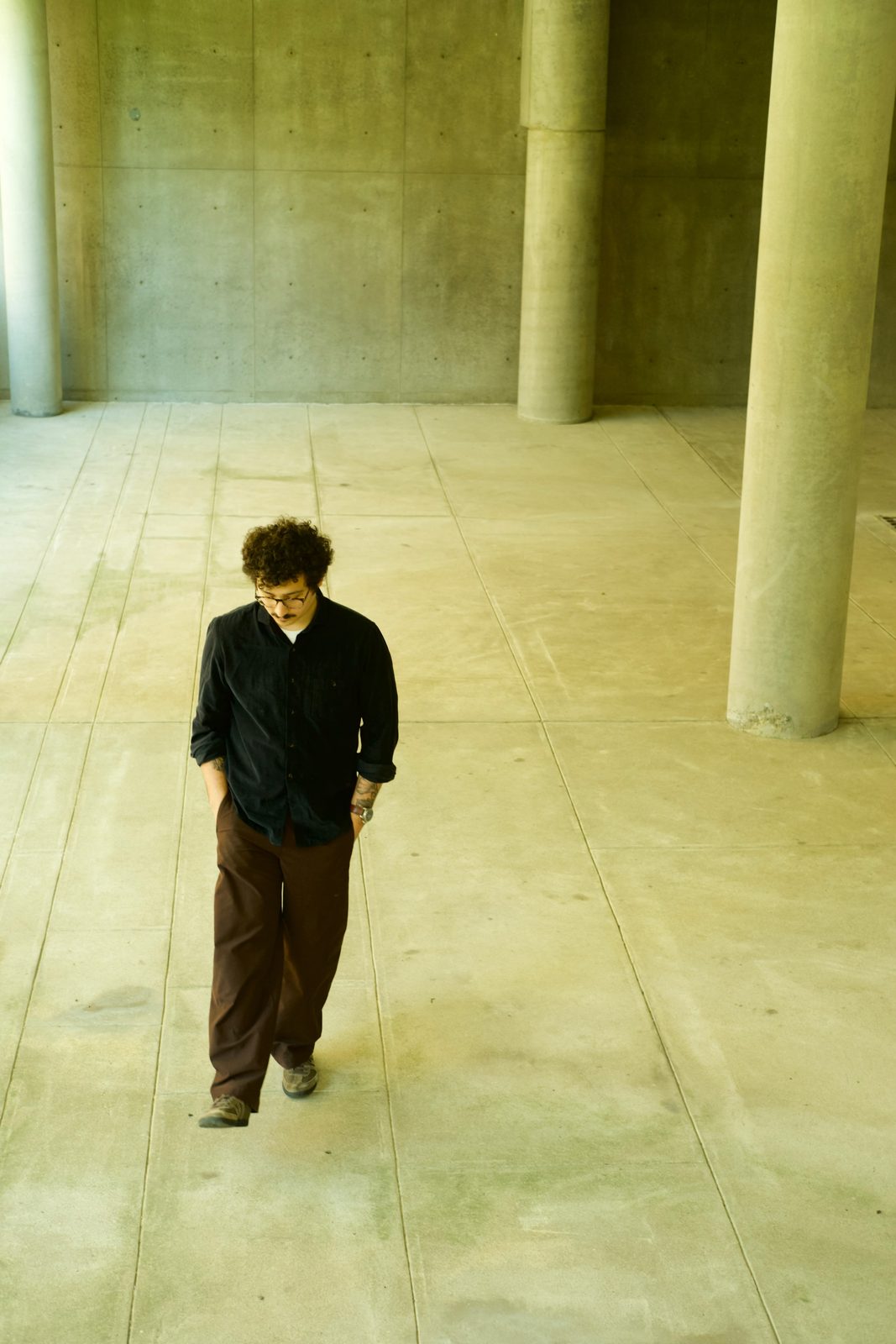 Edu Herédia walking through a concrete colonnade